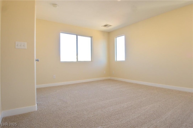 unfurnished room featuring visible vents, baseboards, and light colored carpet