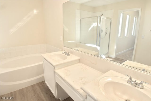 bathroom featuring a shower stall, vanity, a bath, and wood finished floors