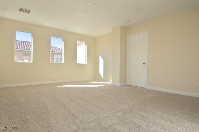 spare room featuring light carpet, visible vents, and baseboards