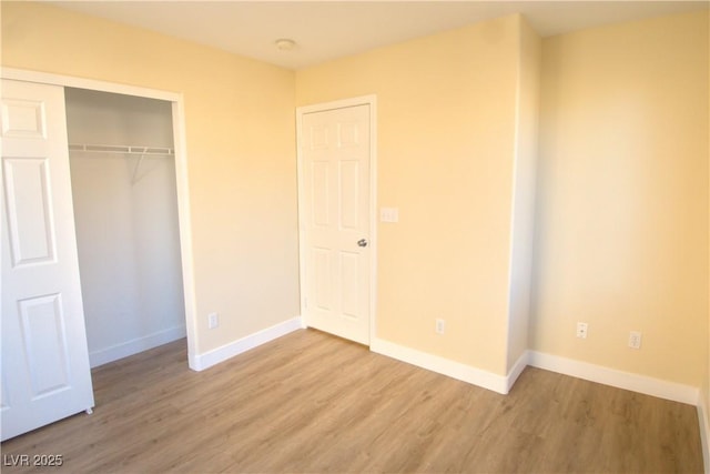 unfurnished bedroom featuring a closet, wood finished floors, and baseboards