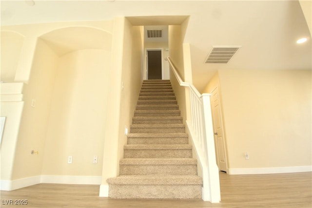 stairs featuring visible vents, baseboards, and wood finished floors