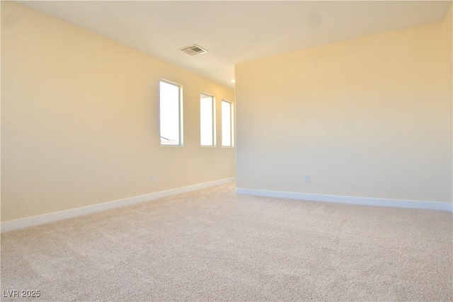 spare room featuring light carpet, visible vents, and baseboards