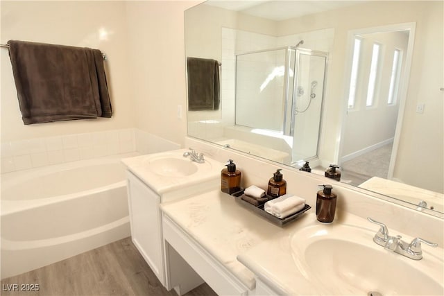 bathroom featuring a stall shower, a garden tub, vanity, and wood finished floors