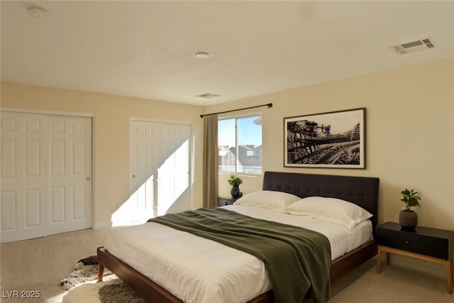 carpeted bedroom with visible vents and multiple closets