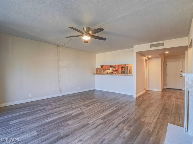 unfurnished living room with baseboards, visible vents, a ceiling fan, and wood finished floors