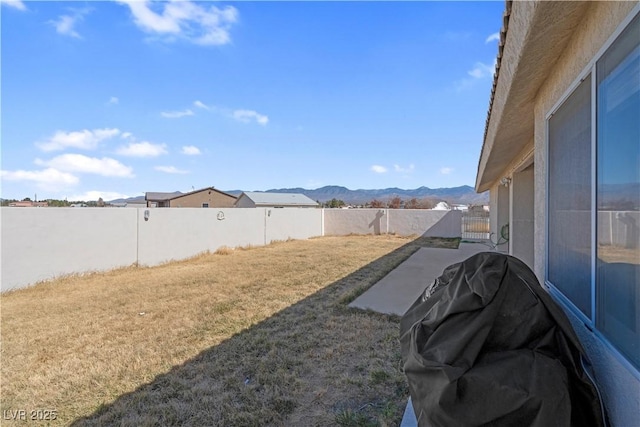 view of yard featuring a patio, a fenced backyard, and a mountain view