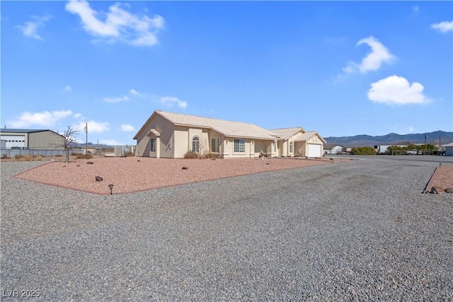 ranch-style home with a garage, a mountain view, and stucco siding