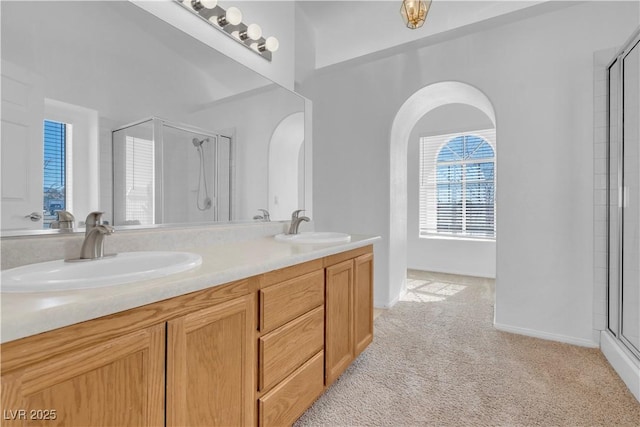 full bathroom featuring a shower with door, a sink, and double vanity