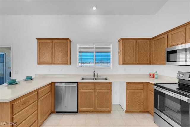 kitchen with a peninsula, stainless steel appliances, a sink, and light countertops