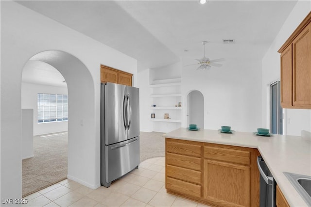 kitchen with light carpet, arched walkways, and stainless steel appliances