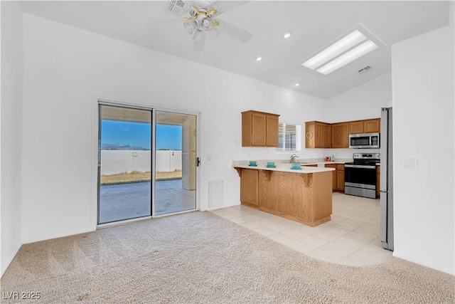 kitchen with light carpet, stainless steel appliances, a peninsula, and visible vents