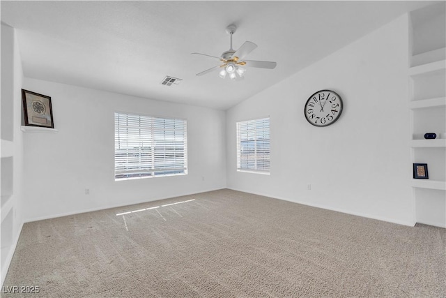 carpeted empty room with lofted ceiling, built in features, visible vents, and a ceiling fan