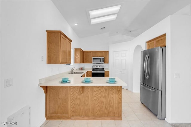 kitchen with stainless steel appliances, light countertops, visible vents, vaulted ceiling, and a peninsula