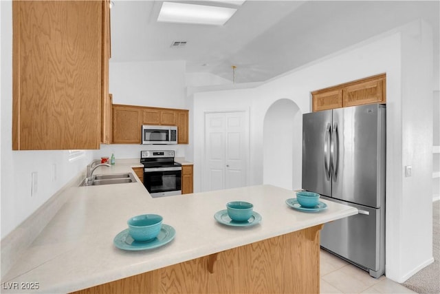 kitchen featuring light countertops, visible vents, appliances with stainless steel finishes, a sink, and a peninsula