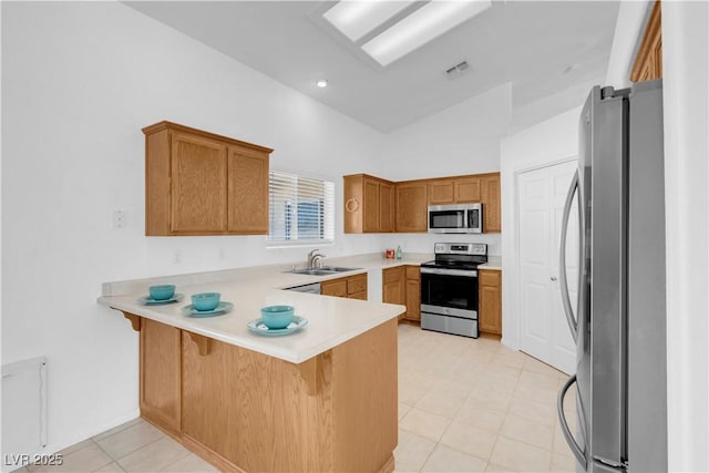 kitchen featuring visible vents, appliances with stainless steel finishes, a peninsula, light countertops, and a sink