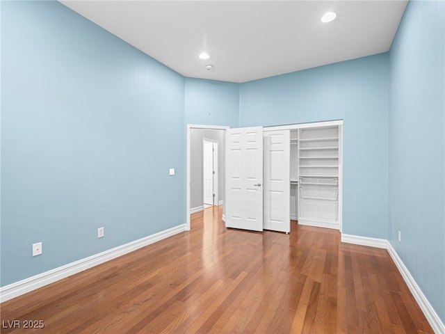 unfurnished bedroom featuring a closet, recessed lighting, wood finished floors, and baseboards