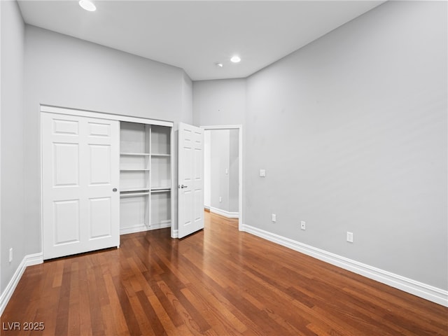 unfurnished bedroom with a closet, recessed lighting, wood finished floors, and baseboards