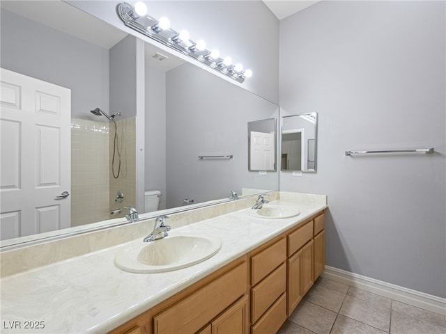 bathroom with double vanity, a sink, toilet, and tile patterned floors