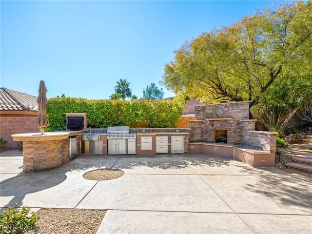 view of patio / terrace with an outdoor stone fireplace, grilling area, and an outdoor kitchen