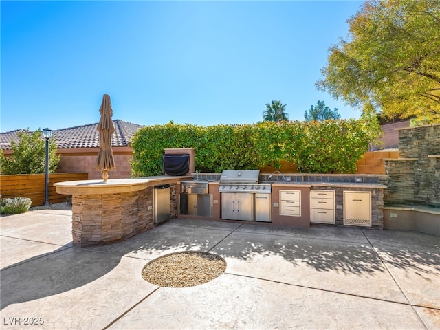 view of patio / terrace with a grill, fence, and exterior kitchen