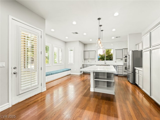 kitchen with visible vents, freestanding refrigerator, gray cabinets, light countertops, and open shelves