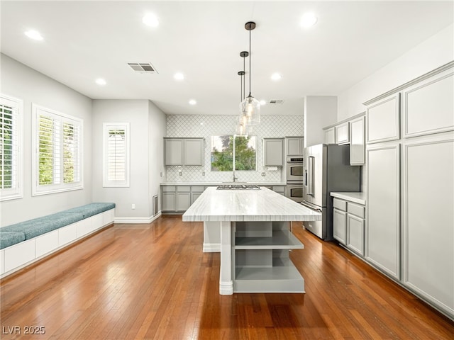 kitchen with visible vents, appliances with stainless steel finishes, gray cabinetry, open shelves, and backsplash