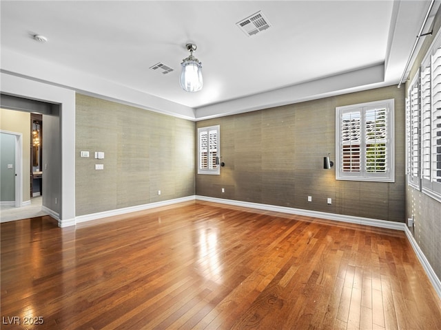 unfurnished room with hardwood / wood-style flooring, baseboards, and visible vents