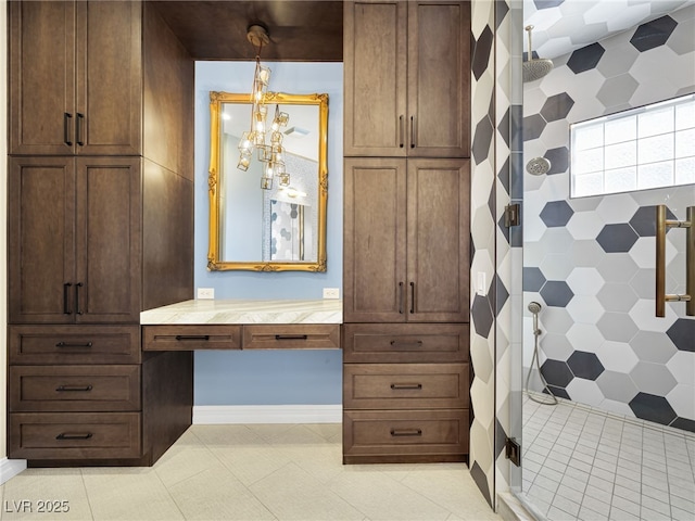 interior space featuring vanity, a chandelier, a tile shower, and tile patterned floors