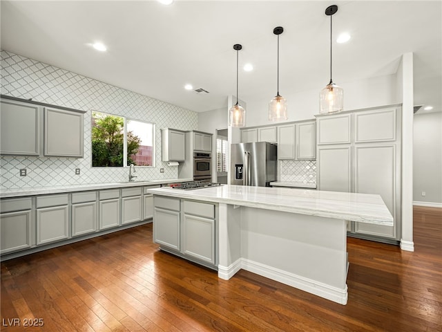 kitchen with stainless steel appliances, dark wood finished floors, a sink, and gray cabinetry