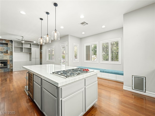 kitchen with a large fireplace, visible vents, hardwood / wood-style flooring, open floor plan, and stainless steel gas cooktop