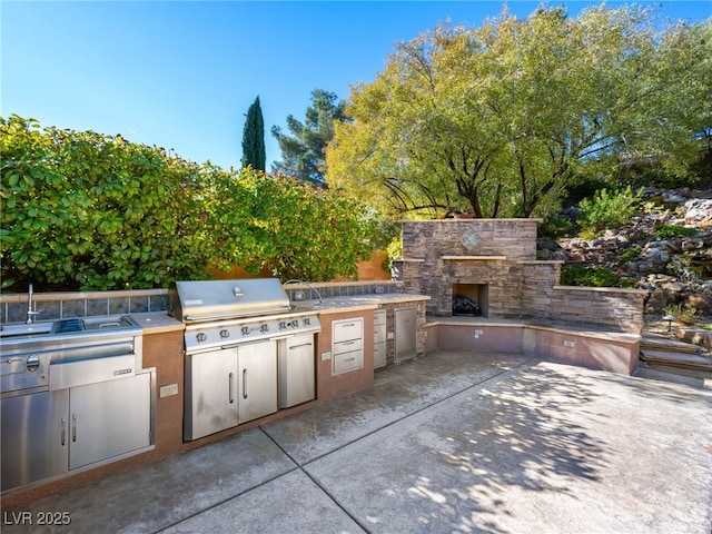 view of patio with grilling area, an outdoor stone fireplace, and an outdoor kitchen