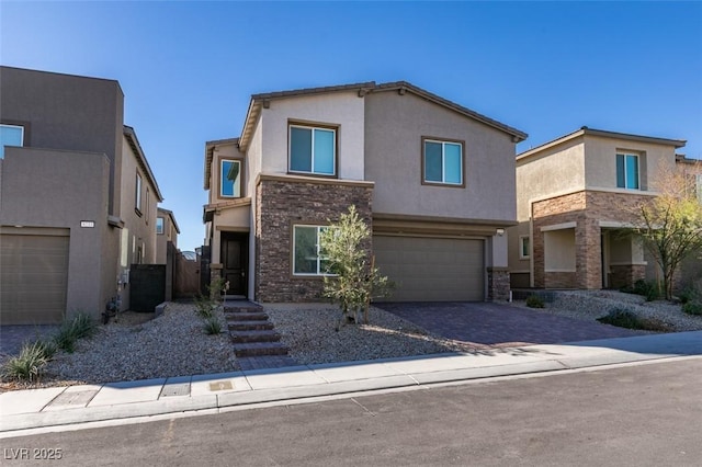 traditional-style house with a garage, stone siding, decorative driveway, and stucco siding