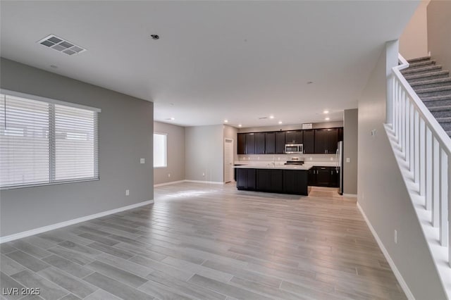 kitchen with baseboards, open floor plan, light countertops, visible vents, and stainless steel appliances