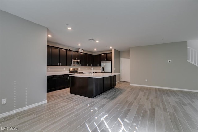 kitchen with light wood-type flooring, appliances with stainless steel finishes, a sink, and light countertops