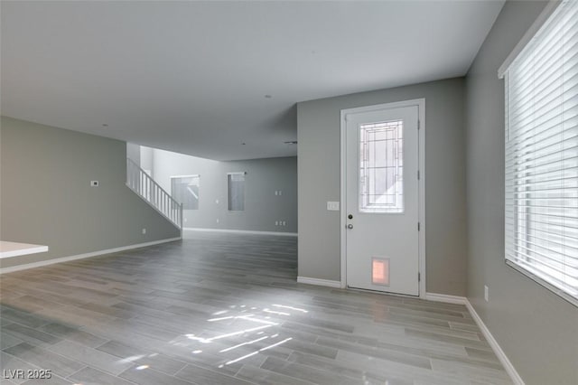 entrance foyer featuring light wood finished floors, baseboards, and stairs
