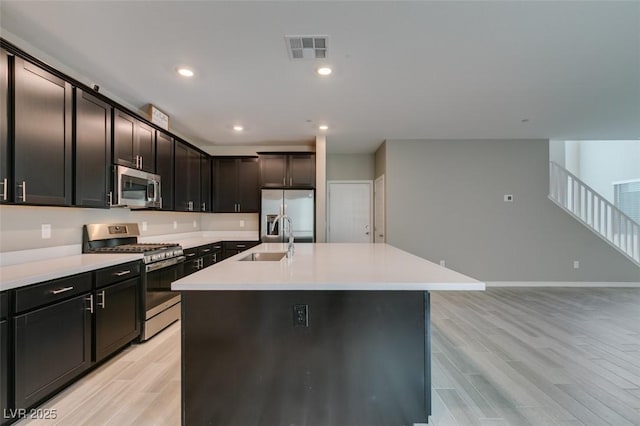 kitchen with light wood-style flooring, visible vents, appliances with stainless steel finishes, a sink, and light countertops