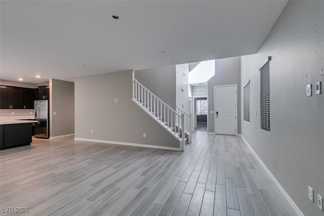 interior space with stairway, light wood-type flooring, and baseboards