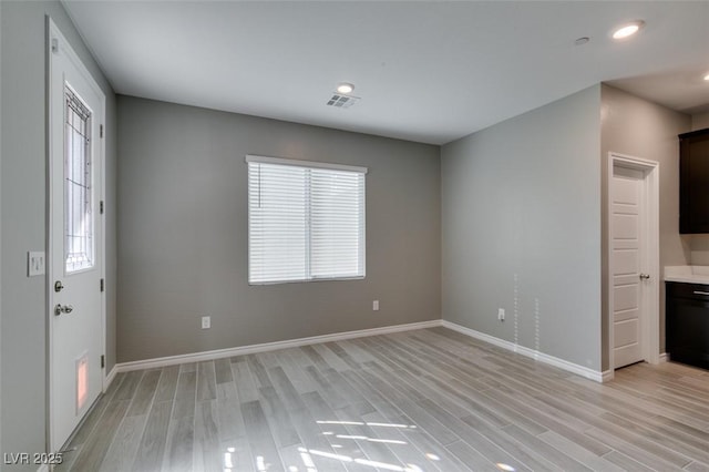 interior space with light wood-type flooring, baseboards, recessed lighting, ensuite bath, and visible vents
