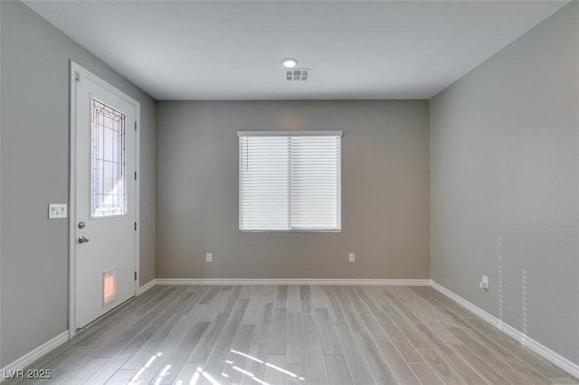 foyer entrance with light wood-style floors, baseboards, and visible vents
