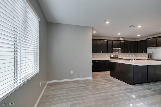 kitchen with light wood-type flooring, baseboards, light countertops, visible vents, and appliances with stainless steel finishes
