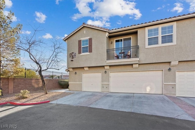 view of property with stucco siding, concrete driveway, fence, a balcony, and a garage