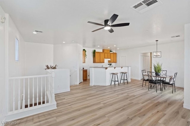 living area featuring light wood-style floors, recessed lighting, visible vents, and ceiling fan with notable chandelier