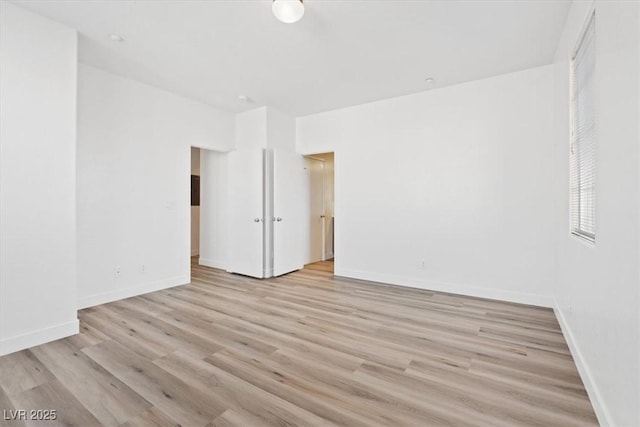 empty room featuring light wood-type flooring and baseboards