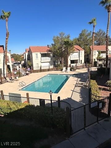 community pool with a patio area and fence