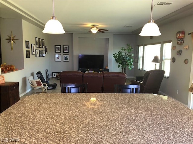 interior space with open floor plan, decorative light fixtures, visible vents, and ceiling fan