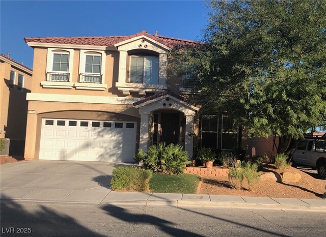 mediterranean / spanish-style house with a tile roof, a garage, driveway, and stucco siding