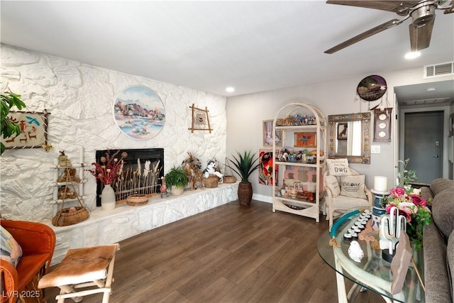 living area with a fireplace, wood finished floors, visible vents, and a ceiling fan