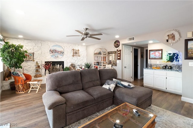 living room with recessed lighting, a fireplace, wood finished floors, visible vents, and wet bar