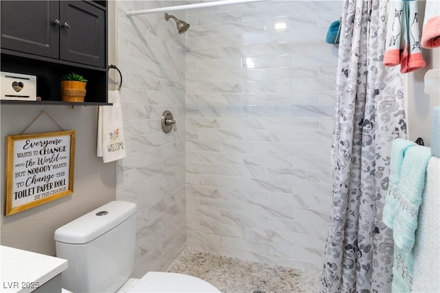 bathroom with tiled shower, vanity, and toilet