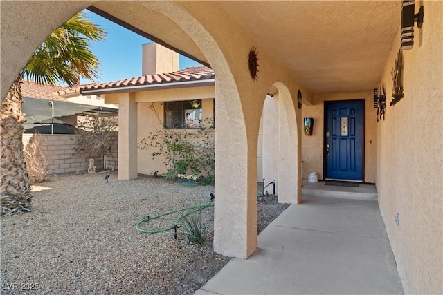 entrance to property featuring a tile roof and stucco siding